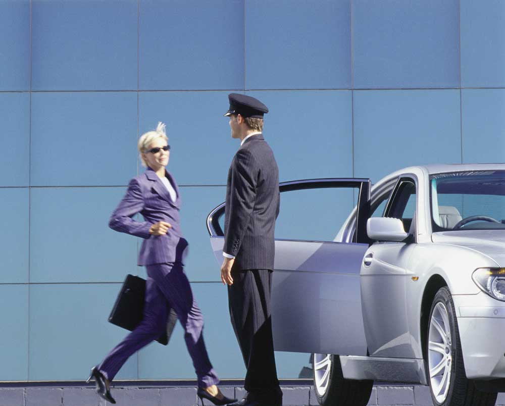 A chauffuer opening the door for a business woman at the airport. AirportLimo providing car services to or from Stinson Airport